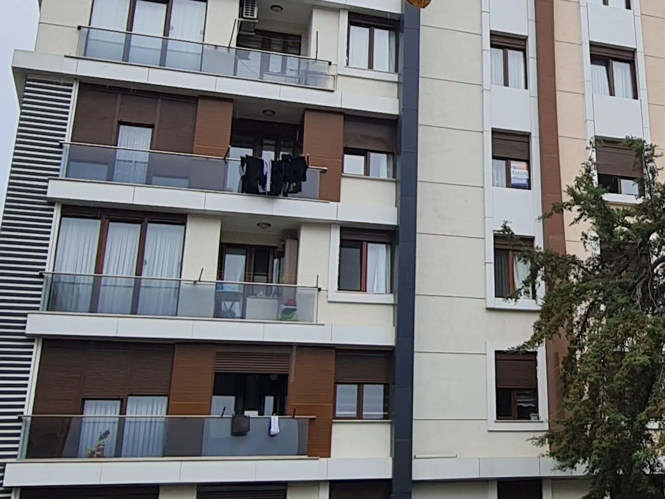 Tunç Apartments wood-toned panels and glass-railed balconies