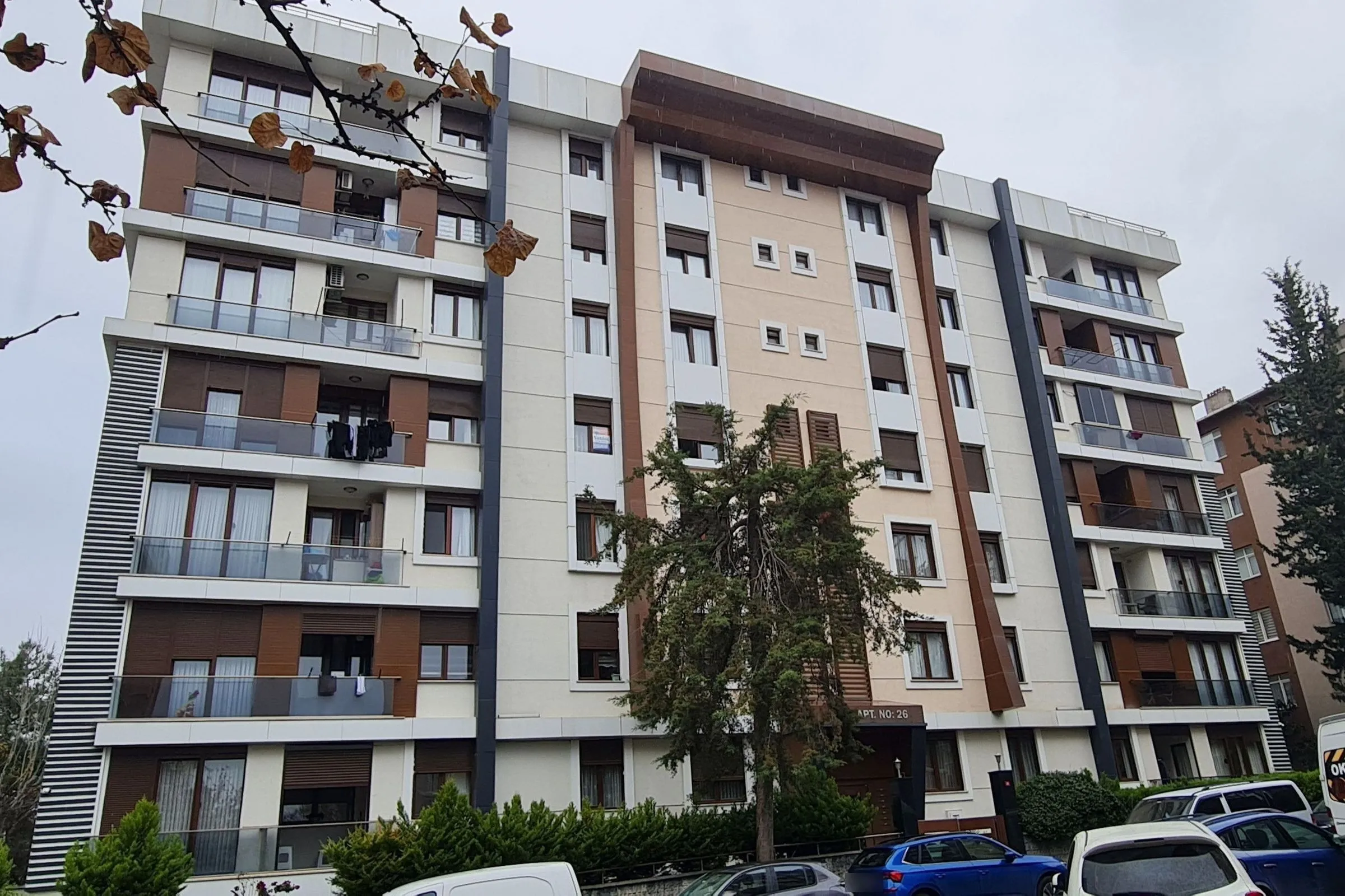 Tunç Apartments in Altayçeşme: a tall residential building with a cream and brown façade, a bronze crown canopy and anthracite vertical columns